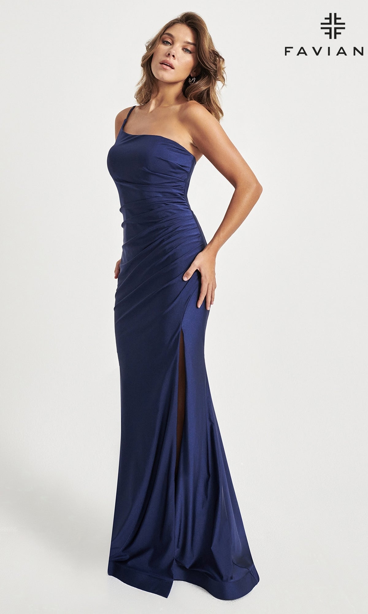 A woman poses in the Faviana One-Shoulder Long Prom Dress 11071, a fitted gown featuring a thigh-high slit. She stands against a plain white background with the Faviana logo visible in the top right corner.